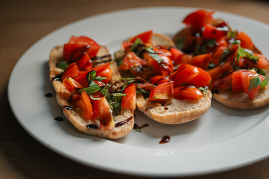 Fresh bruschetta on white plate with tomatoes, basil and balsamic vinegar
