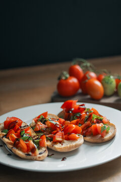 Freshly made bruschetta with bunch of tomatoes in background
