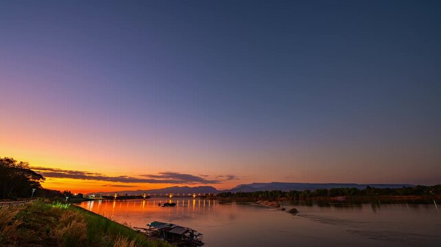 Time lapse Golden twilight illuminates the Fifth Thai&ndash;Lao Friendship Bridge as it spans the Mekong River, highlighting a new landmark of northeastern Thailand at dusk. Dreamy Skies at Sunset