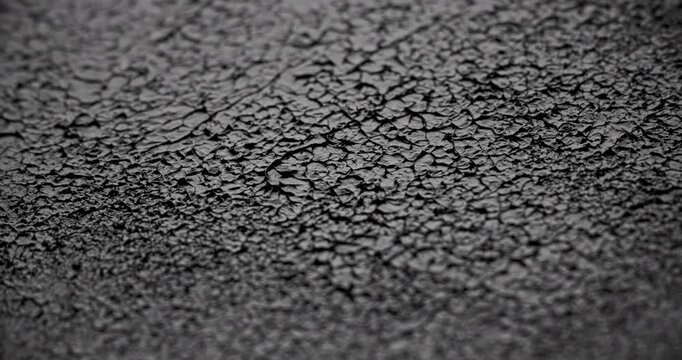 Macro Cracked Mud Texture on Black. Slow panning footage across a fissured dark surface.