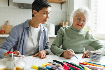 Alzheimer treatment game at home, old lady with gray hair in glasses and her female home assistant...