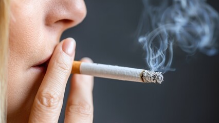 Extreme close up of a woman smoking a burning cigarette with smoke