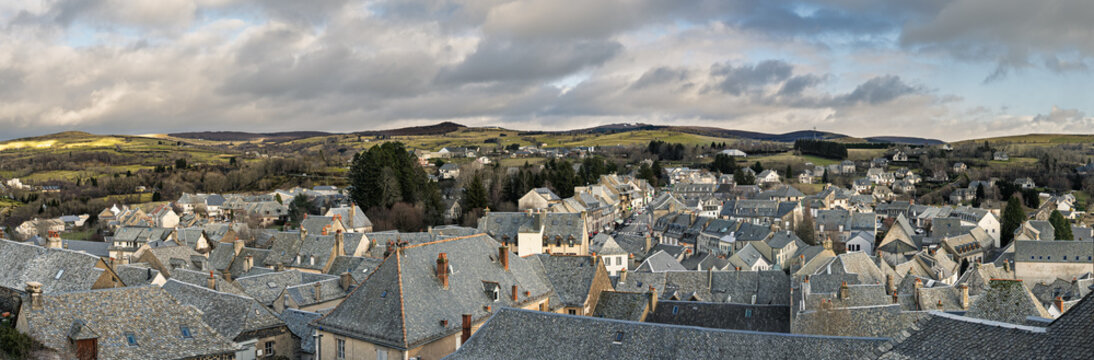 Laguiole village panorama in Aveyron, France. Traditional stone houses with slate rooftops surrounded by rolling hills of the Aubrac plateau