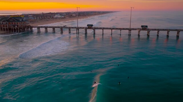 Surfing by the pier at sunset