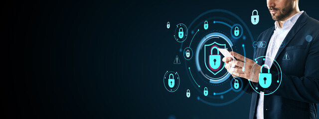 Businessman using smartphone with digital lock icons and shield security symbol on dark abstract...