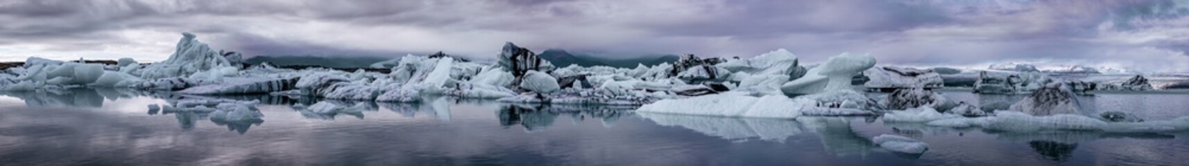Ultra wide panorama of the Jokulsarlon Glacial lagoon, Southern Iceland. Mirror reflection of the blue ice icebergs. © Rixie