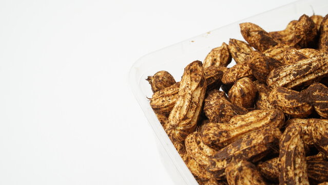 Isolated white batik peanuts or striped peanuts (Arachis hypogaea L.) that are still dirty with soil and have not been washed are placed in clear plastic containers.