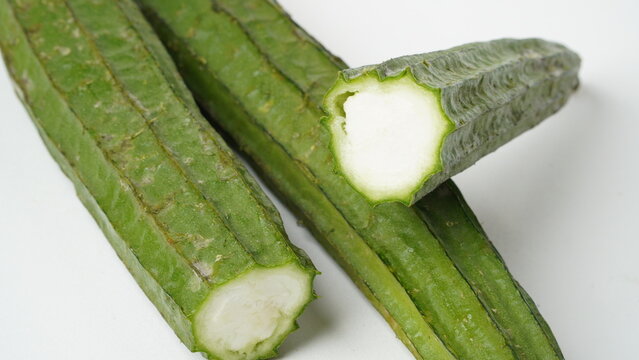 Isolated white photo of a vegetable called oyong or gambas (Luffa acutangula) which is long, has green skin and a hard texture with a white inside.