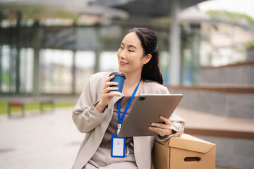 Fototapeta premium Portrait of a successful business woman using smartphone and digital tablet in front of modern business building.