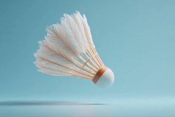 Closeup of a white badminton shuttlecock floating in mid air against a light blue studio background. Clean and minimalist sports equipment concept.