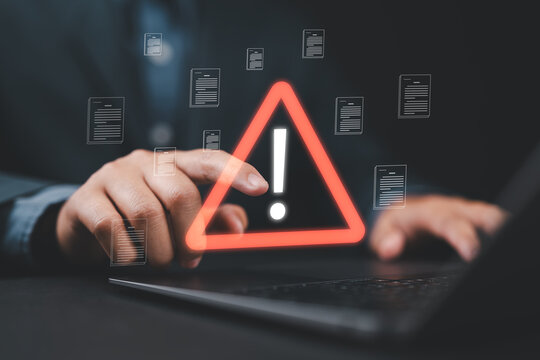Close-up of person pointing at personal data and documents with warning sign, symbolizing data breach, cyberattack, hacker intrusion, spyware risk, and digital security protection concept.