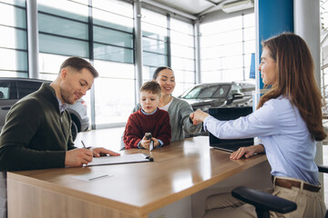 Family buying new car at dealership signing contract, receiving key from saleswoman, happy parents...