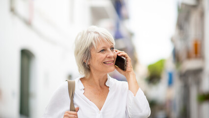 Fototapeta premium Happy senior woman talking on smartphone outdoors