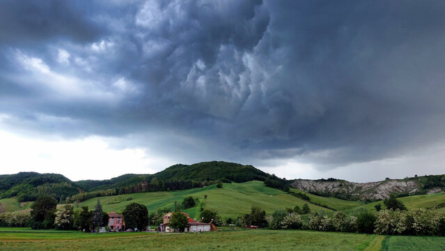Dramatic storm clouds over the green hills of Val Termina, Italy.