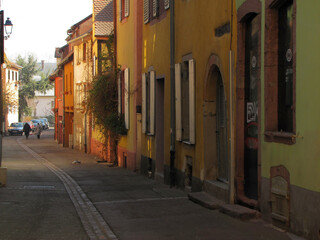 Fototapeta premium Charming Alsace village street with colorful half-timbered houses, narrow cobblestone path, historic architecture, and tranquil pedestrian atmosphere, FR, 05 March 2011