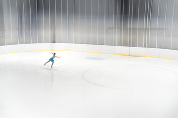 Graceful figure skater performing a spin on an empty ice rink © phaitoon