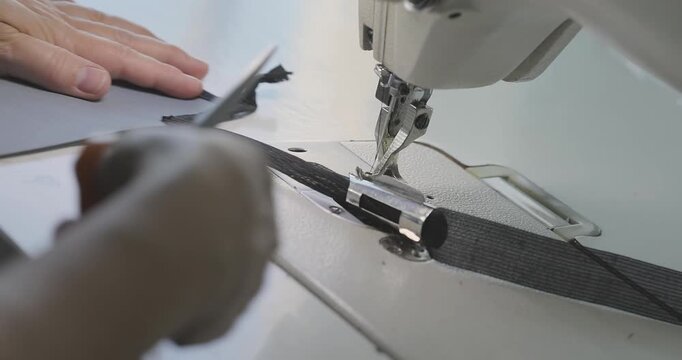 A worker sews a seam on thick upholstery fabric for a shipbuilding, shipyard or furniture factory. A close-up of a woman's hands and an industrial sewing machine. Close-up. Macro