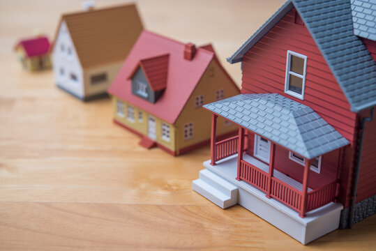 The houses are lined up from smallest to largest on wooden table with copy space. Upsizing house, homebuyer financial planning, mortgage loan, banking, construction industry and so on concept.