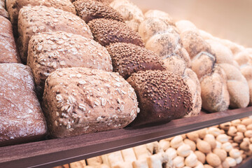 Variety of breads are displayed on shelf, including some with nuts and others with seeds