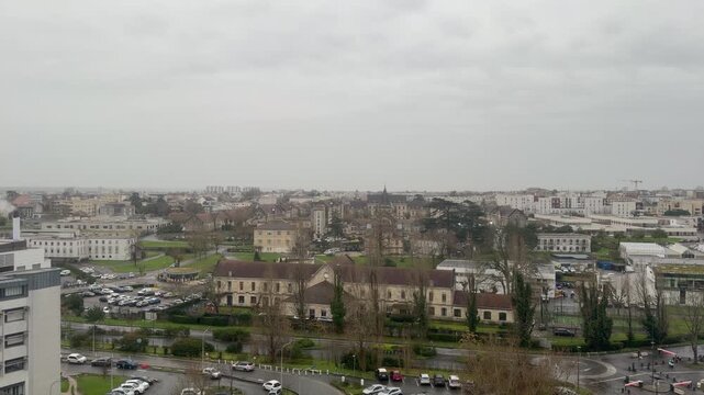 4K static shot of the Pellegrin University Hospital area and parking lots in Bordeaux, France. High-angle view of urban infrastructure, buildings and city traffic under an overcast sky