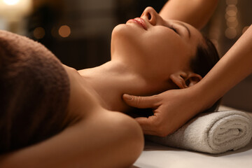 Naklejka premium Beautiful woman having facial massage in dark spa salon, closeup
