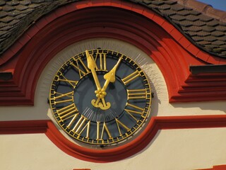 Obraz premium Close-up of the black and gold Roman numeral clock set in the red and white facade of Emmendinger Tor in Emmendingen, 08 March 2011