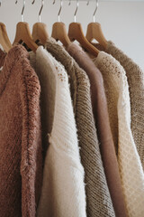 Collection Of Warm Woolen Jumpers Arranged By Color On A Minimalist Clothing Rack