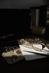 Minimalist Business Scene With Laptop Keyboard, Eyeglasses, Clipboard, And Office Accessories In Shadow