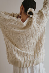 Woman Wearing Knitted Sweater with Arms Raised. Neutral lifestyle scene with oversized cream knit sweater, soft light