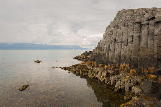 Basalt cliff reflected in calm Icelandic water