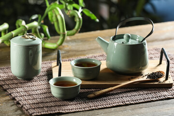 Tray with cups and teapot of hot tea on wooden table outside