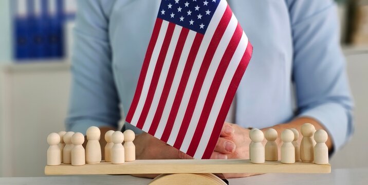 A person placing a wooden flag in front of small figures representing a community gathering
