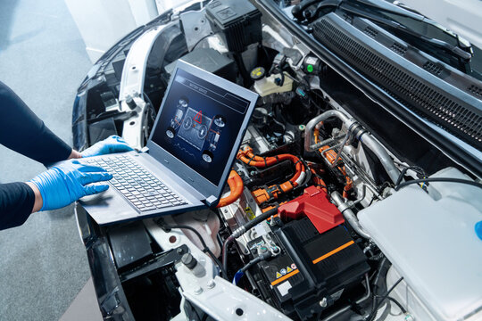Technician checks the battery pack of an electric car at a service center.