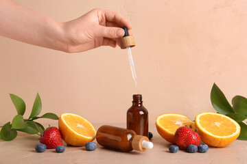 Female hand with natural cosmetic oil and fruits on beige background