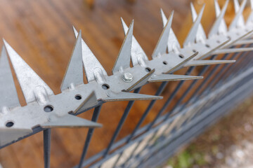 Close-up of Sharp galvanized metal anti-climb spikes mounted on a security fence for perimeter protection and security