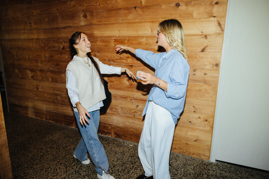 Happy Gen Z colleagues sharing a warm greeting at work