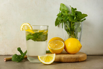 Glass of water with lemons, mint leaves and straw on brown grunge table © Pixel-Shot