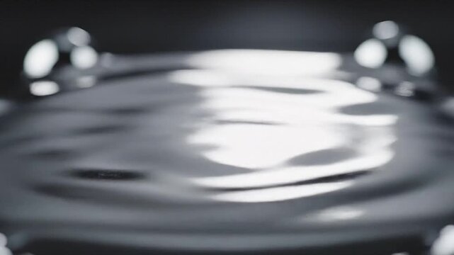 A macro shot of beads of liquid mercury merging into one reflective pool.