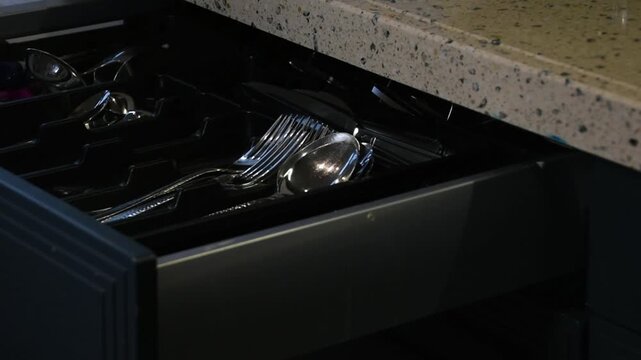Man opens kitchen drawer and takes out a tablespoon