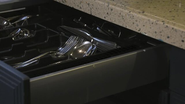 Man opens kitchen drawer and takes out fork and tablespoon