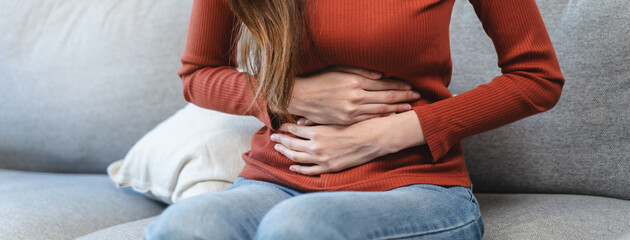 Naklejka na ściany i meble asian young woman intolerance hand in stomach ache, suffer from food poisoning, abdominal pain and colon problem