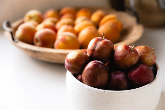 Bowls of freshly picked peaches and plums on kitchen bench