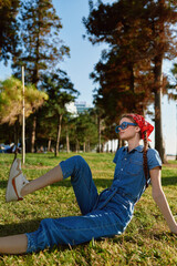 Lifestyle woman in modern boho-western denim street style relaxing outdoors under warm sunlight with vibrant film color tones and nature background.