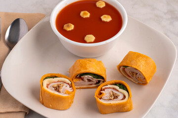 turkey pin wheel sandwich  with  a bowl oftomato soup