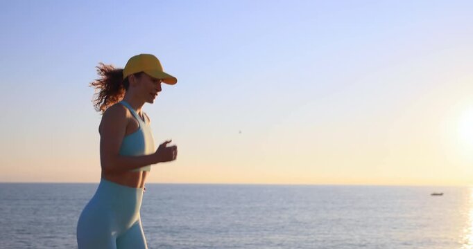 Athlete woman runner got sports injury in low back running at the beach. Slow motion