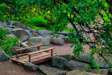 Fototapeta premium Small wooden bridge crosses a rocky terrain stream spring national park decorative scenic view from above April month day