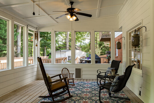 Sunroom with rocking chairs and large windows viewing wooded backyard