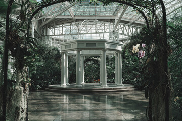 White neoclassical gazebo inside a lush botanical garden conservatory © Trey