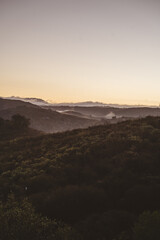 Obraz premium Misty hills and rolling mountains at sunrise with copy space