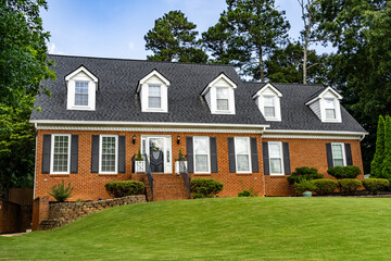 Two story red brick house with green lawn and dormer windows